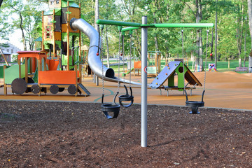 Empty colorful playground with swings and slides for children  with soft orange protective rubber...