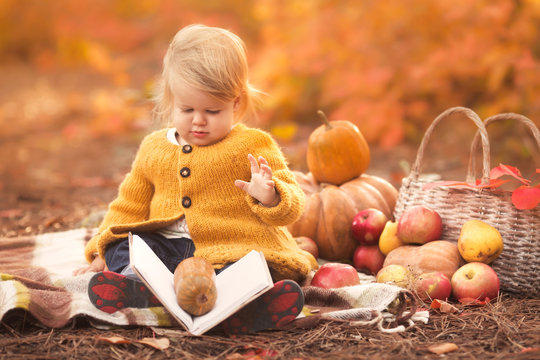 Little girl reading her first book at autumn park