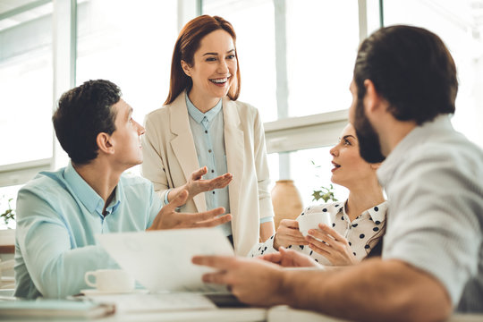 Team leader. Positive cheerful woman smiling while looking at her team