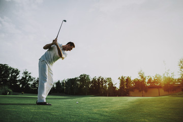 Young Man in White Clothes Playing Golf on Field.