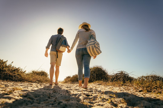 Rear view of a couple walking on beach sand