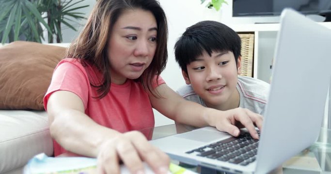 Young Asian mother working  on the laptop computer with his son with smile face .