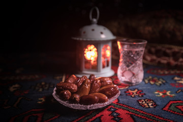 Water and dates. Iftar is the evening meal. View of decoration Ramadan Kareem holiday on carpet. Festive greeting card, invitation for Muslim holy month Ramadan Kareem. Dark background