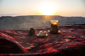 Eastern black tea in glass on a eastern carpet. Eastern tea concept. Armudu traditional cup. Sunset background.