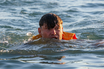 A man is swimming on the sea at sunset