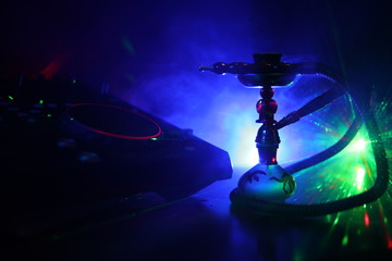 Shisha party club concept. Dj mixer with on dark nightclub background with stylish oriental shisha.