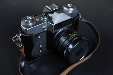 Fototapeta na wymiar Retro style film photo camera with lens on black background. Front top side view