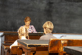 Concept of public primary school education with young boy and girl listening to the female teacher