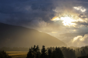 Dramatic rain clouds and thick mist at sunset, in the mountains, in summer