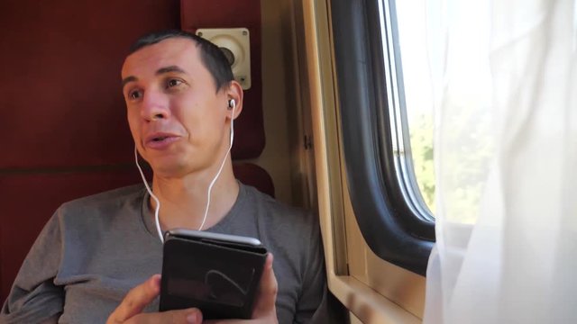 man listening to the music on the train rail car coupe compartment travel. slow motion video. man with a smartphone at the window of a train in a car travel internet social media web. man train