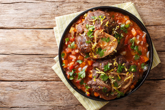 Delicious Italian veal steak Ossobuco alla Milanese with gremolata and vegetable sauce close-up. horizontal top view