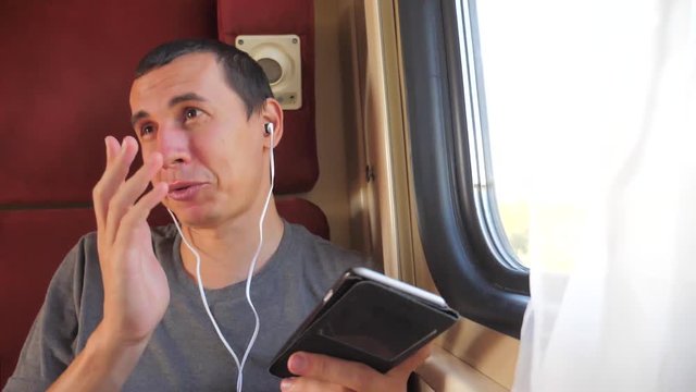 man listening to the music on the train rail car coupe compartment lifestyle travel. slow motion video. man with a smartphone at the window of a train in a car travel internet social media web. man