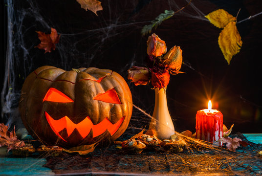 Halloween photo of table with pumpkin, biscuits, dried flowers, burning candle