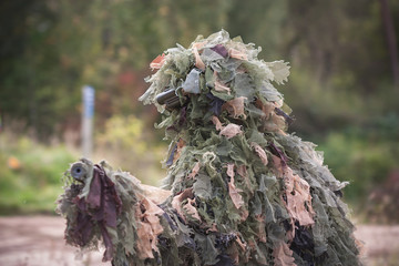 Sniper wearing ghillie camouflage in action