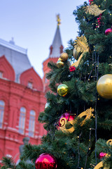 Christmas tree decorated with balls and garlands on red square background in Moscow