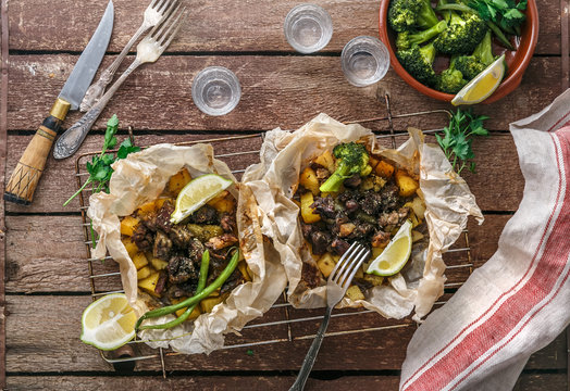 Traditional Greek kleftiko, an oven-baked lamb stew with potato, olive oil, onion, carrot, garlic and herbs, served with lemon and ouzo.