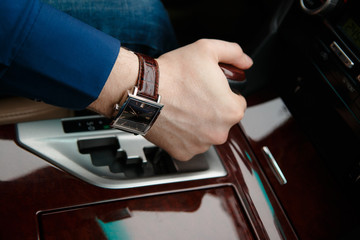 Businessman driving his car, hand on the steering wheel. Hand with golden watch. Business concept.