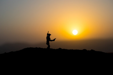 Cowboy concept. Silhouette of Cowboys at sunset time. A cowboy silhouette on a mountain with an yellow sky.