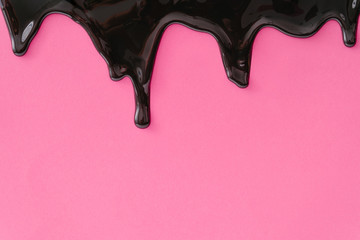 Pastel pink background with black dripping paint. Minimal makeup or fashion concept.