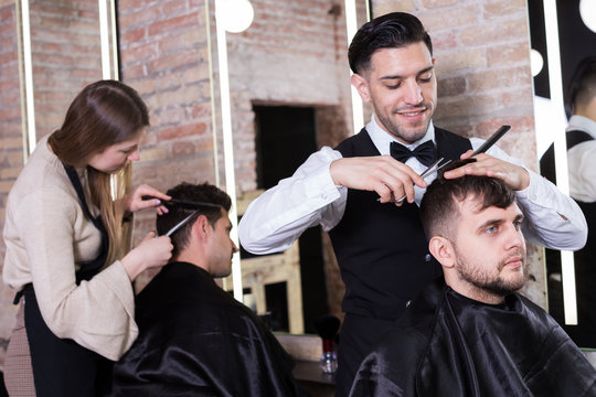 Barber making haircutting for male client
