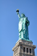 Fototapeta na wymiar statue de la liberté, prise en contre plongée un matin par un ciel bleu totalement dégagé, à Ellis Island New York, Etats-Unis