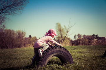 Obraz premium Portrait of a child playing with a big car tire in the park