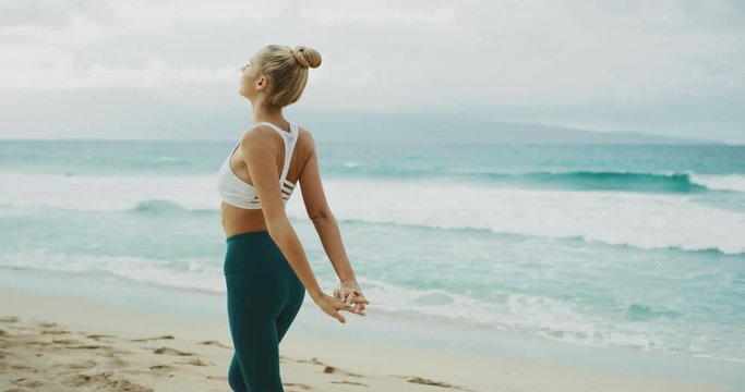 Fitness lifestyle of beautiful young woman stretching and practicing yoga at the beach