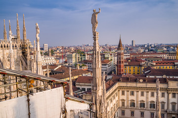Fototapeta na wymiar Rooftop view of spires, sculpture, cathederal, and Milan from the Duomo di Milano at sunset