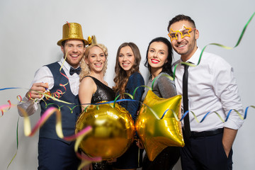 celebration, fun and holidays concept - happy friends with golden party props and confetti laughing