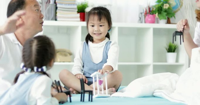 Happy asian family with two daughters playing at home. Family sitting on floor and playing together.