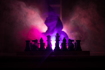 Man playing chess. Scary blurred silhouette of a person at the chessboard with chess figures. Dark toned foggy background.