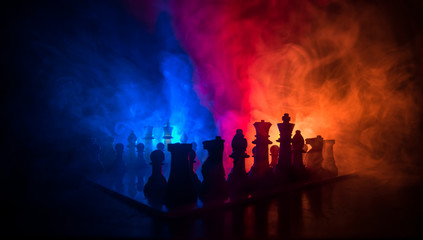 Chess board game concept of business ideas and competition or strategy ideas concept. Chess figures on a dark toned foggy background.