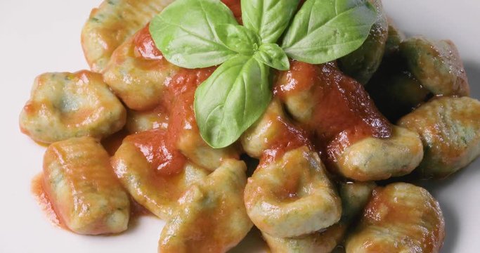 Gnocchi di patate fatti in casa verdi con salsa al pomodoro e basilico fresco su un piatto da esposizione per un ristorante. Cibo vegetariano