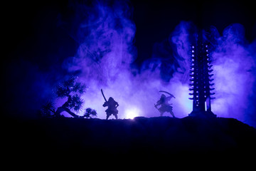 Samurai fighting concept. Silhouette of samurais in duel near tree and old temple. Picture with two samurais and sunset sky. Selective focus