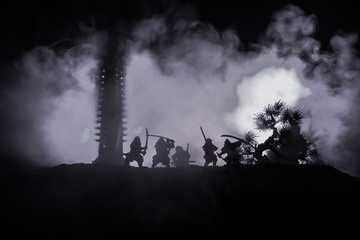 Fototapeta na wymiar Samurai fighting concept. Silhouette of samurais in duel near tree and old temple. Picture with two samurais and sunset sky. Selective focus