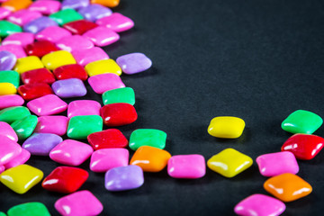 chewing gum of different colors on a black background