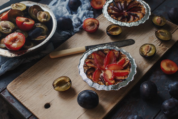 Homemade pie of fresh organic plums on wooden board and rustic table. Seasonal healthy vegeterian food, autumn dessert,  selective focus