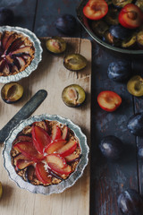 Homemade pie of fresh organic plums on wooden board and rustic table. Seasonal healthy vegeterian food, autumn dessert,  selective focus