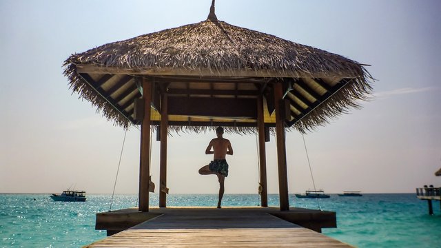 Yogi in arbor over blue ocean on the island, Maldives.
