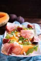 Close up of plate with melon, arugula and prosciutto