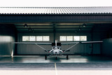 small modern white airplane standing in hangar