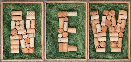 Word New made of wine corks on green background in wooden box