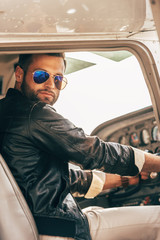 stylish male pilot in leather jacket and sunglasses sitting in airplane © LIGHTFIELD STUDIOS