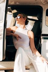 low angle view of young woman in sunglasses sitting near airplane