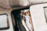 selective focus of handsome man in leather jacket and sunglasses standing with girlfriend near plane