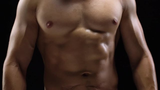Man shows a muscular strong body close-up on a black background