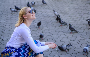 Woman tourist or citizen toss crumbs for pigeons. Girl feeding dove birds. Group doves on city...