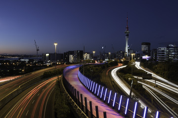 Night view of Auckland City from Hopetoun Street bridge with the motorway junction complex and pink bike path in the foreground. Auckland, New Zealand.
