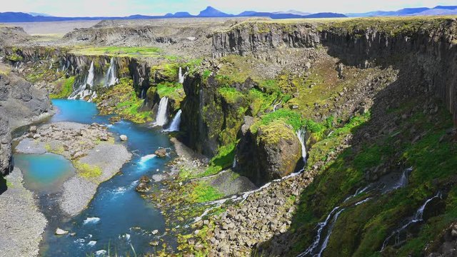 Row of the waterfalls at the cliff of the mountain on the bank of river in Highlands of Iceland