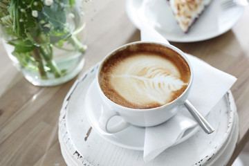 Espresso z mlekiem. Filiżanka gorącej kawy z pięknym zdobieniem na piance.